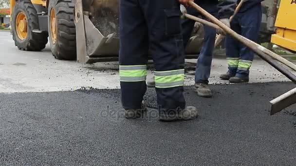 Dělníci jsou vyrovnání horkého asfaltu po na zem, práce na silnici - Záběry, video