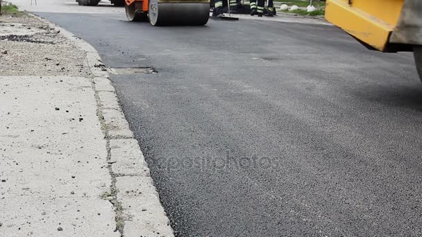 Los trabajadores están nivelando el asfalto caliente después de que se aplica en el suelo, obras de carretera
 - Imágenes, Vídeo