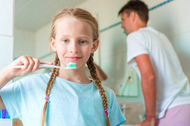 Ragazza felice e papà lavarsi i denti in bagno spazzolini da denti
 - Foto, immagini