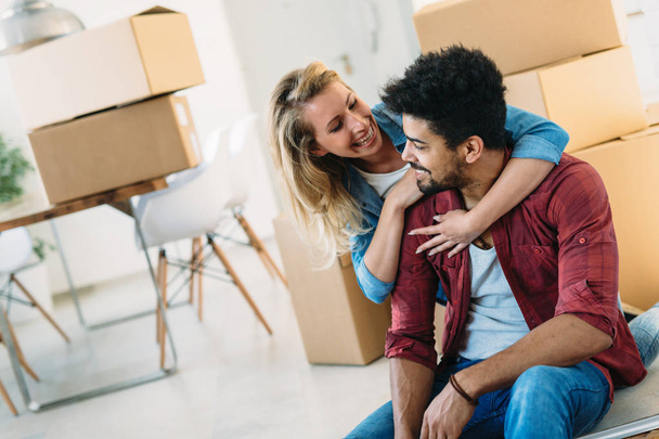 Young couple unpacking cardboard boxes at new home moving in concept - Фото, изображение