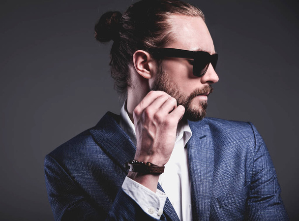 handsome fashion stylish hipster businessman model dressed in elegant blue suit posing on gray background - 写真・画像