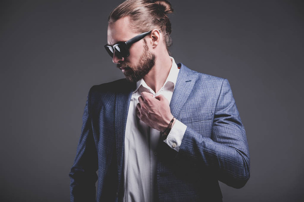handsome fashion stylish hipster businessman model dressed in elegant blue suit posing on gray background - Photo, image