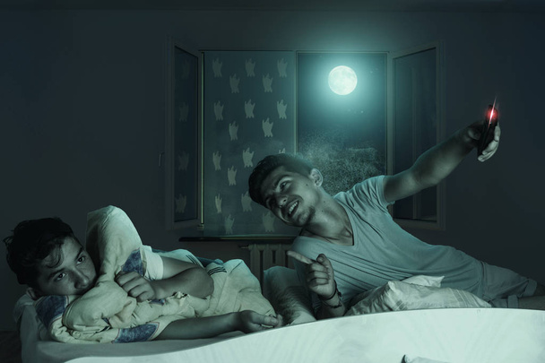 Older brother laugh down the scared and sleepless boy at bedroom - Fotoğraf, Görsel