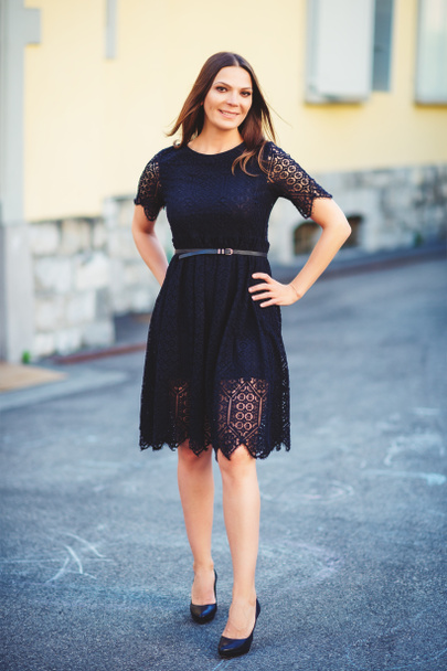 Outdoor portrait of young beautiful brunette woman wearing black lace dress and high heel shoes - Photo, Image