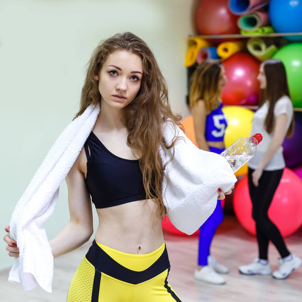 junge Frau mit Handtuch und Wasserflasche in einem Fitnessstudio. - Foto, Bild