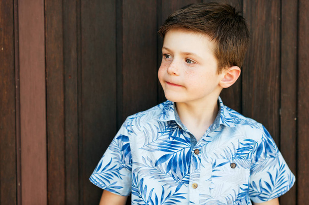Grappige stijlvolle jongen jongen poseren buitenshuis, blauwe print shirt dragen  - Foto, afbeelding