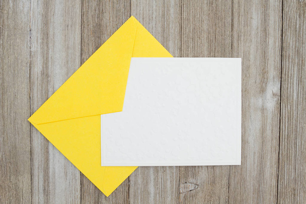Тиснутая белая карточка с желтым конвертом на выветриваемом w
 - Фото, изображение