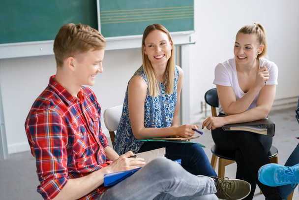 Smiling diverse young students having group discussion in classroom - Photo, Image