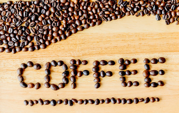 Coffee beans are literally "coffee" on a wooden floor. - Photo, Image