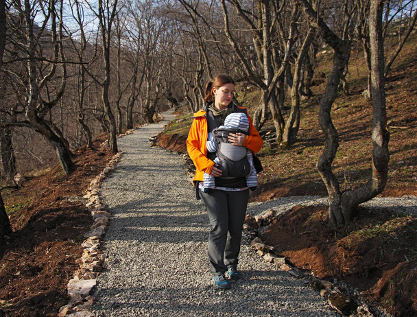 mère avec bébé dans le porte-bébé marche par la route forestière
 - Photo, image