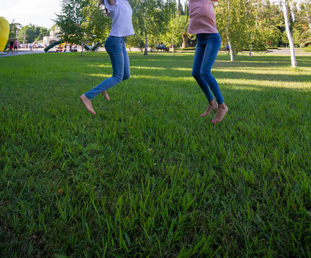 Two teen girl friends jumping on grass - 写真・画像