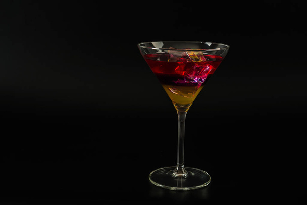 Красочный напиток в коктейльном бокале, с кубиками льда, летний напиток
 - Фото, изображение