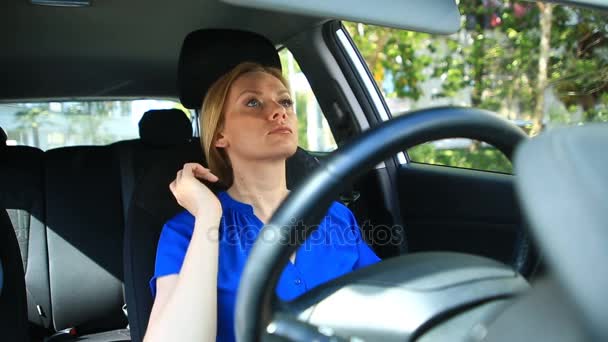 Girl adjusts makeup and hairstyle while sitting at the wheel of car - Πλάνα, βίντεο