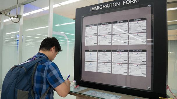 Asia ember utas a bevándorlási formában a vámhatóságok szolgáltatási terület a repülőtér bevándorlási űrlap kitöltésével. Bevándorlási űrlap koncepció. - Fotó, kép
