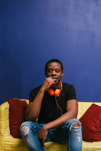 Black man with headphones sit on couch, rest alone - Φωτογραφία, εικόνα