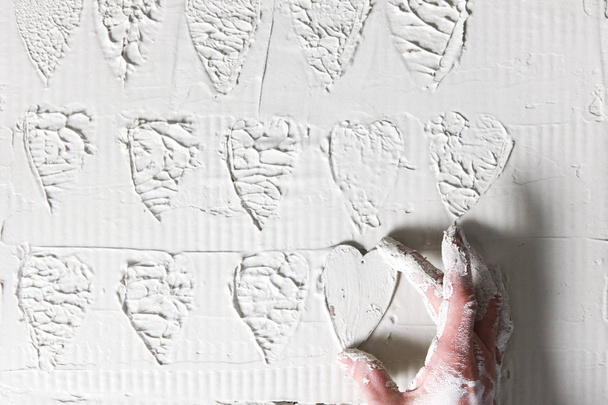 Hand make heart stamps on white plaster wall - 写真・画像