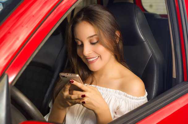Beautiful sexy young woman in red car holding keys and smiling - Foto, imagen