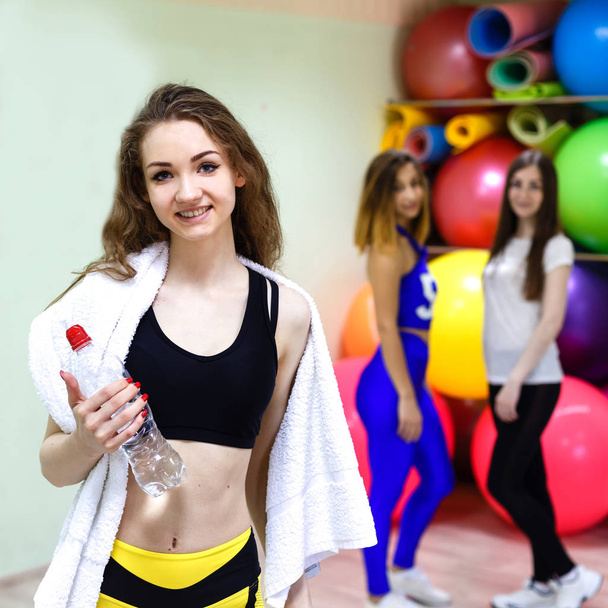 Jeune femme avec une serviette tenant une bouteille d'eau pendant l'entraînement
 - Photo, image