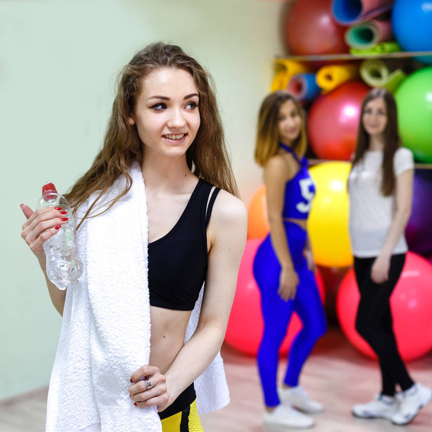 Giovane donna con un asciugamano che tiene una bottiglia d'acqua mentre si allena
 - Foto, immagini
