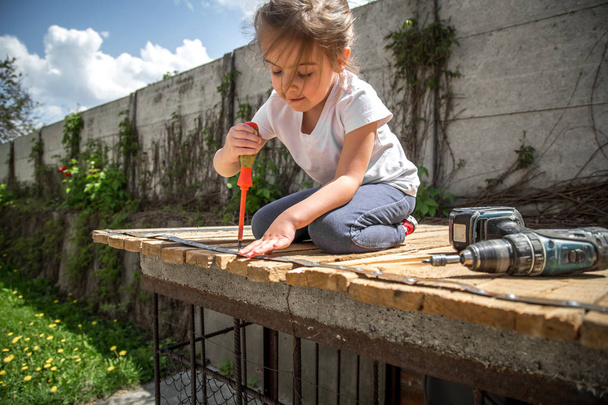 kleines Mädchen repariert mit Schraubenzieher und Schraubenzieher in der Hand - Foto, Bild