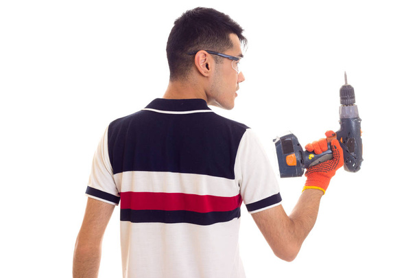 Jonge man met handschoenen en bril houden van elektrische schroevendraaier - Foto, afbeelding