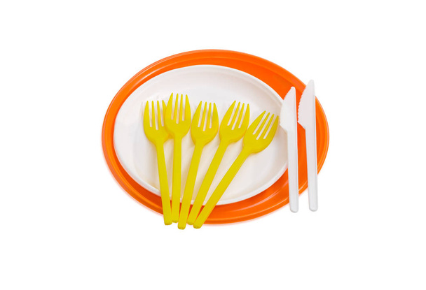 Placas de plástico descartáveis laranja e branco, garfos e facas
 - Foto, Imagem