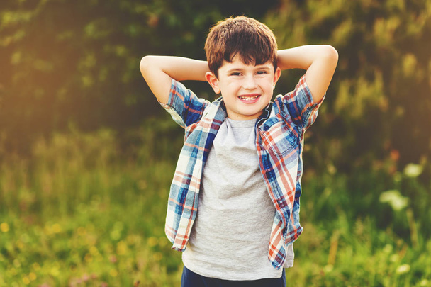 6 yaşındaki bir çocuk mutlu çocuk açık havada mavi ekose gömlek giymiş eğleniyor - Fotoğraf, Görsel