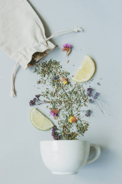 Tea time. Dry herbal tea and cup on the gray background, top view - Photo, image