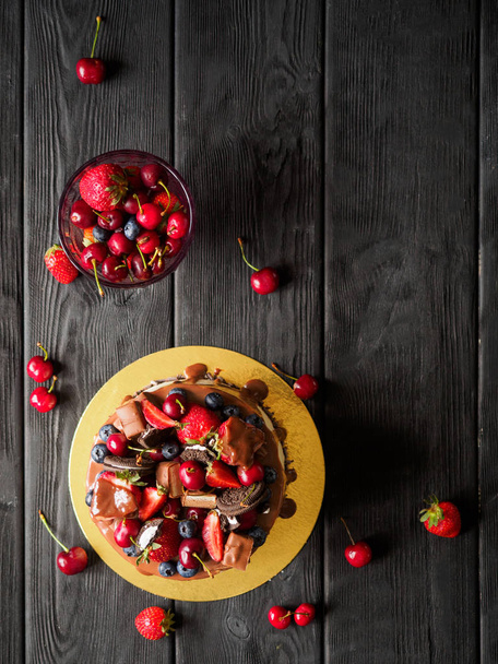 Berry birthday cake with chocolate on black wood desks - Fotoğraf, Görsel