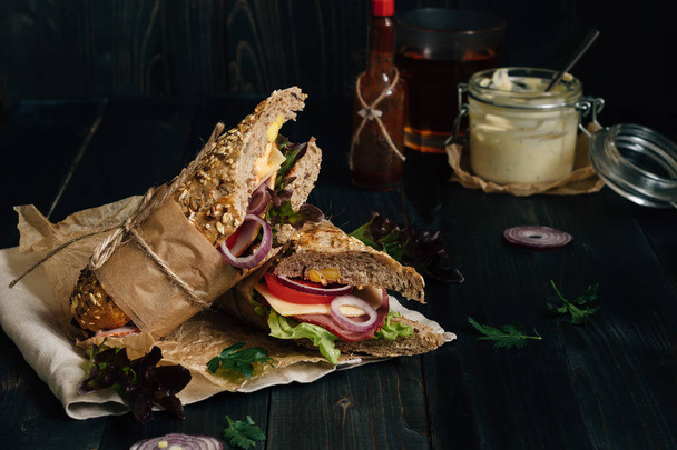 Fresh tasty submarine sandwich and sauces on the wooden dark tab - Fotografie, Obrázek