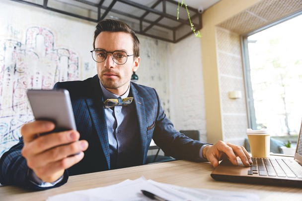 Calm businessman watching at mobile at desk - Foto, imagen