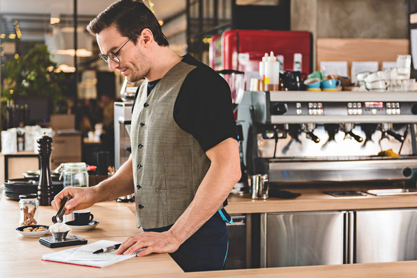 Happy man preparing appetizing coffee in cafe - Photo, Image