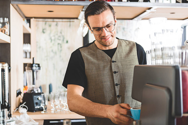 fröhlicher Barkeeper macht Kaffeebecher - Foto, Bild