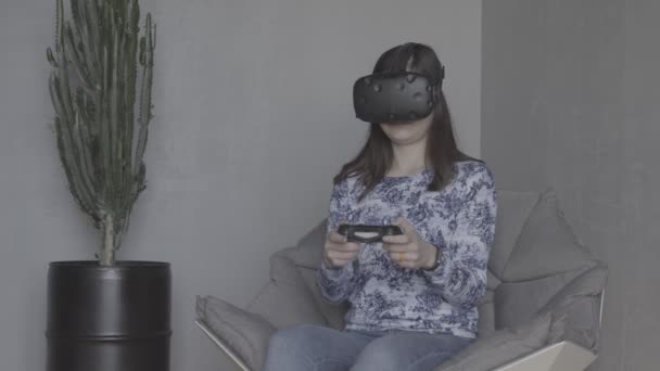 Young woman playing video games with virtual reality headset and joystick - Footage, Video