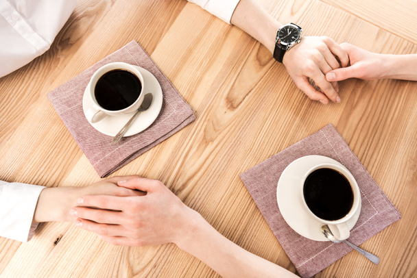 girlfriends holding hands while drinking coffee - Fotografie, Obrázek