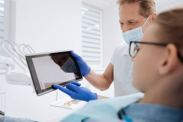 dentist using gadget for explanation - Фото, изображение
