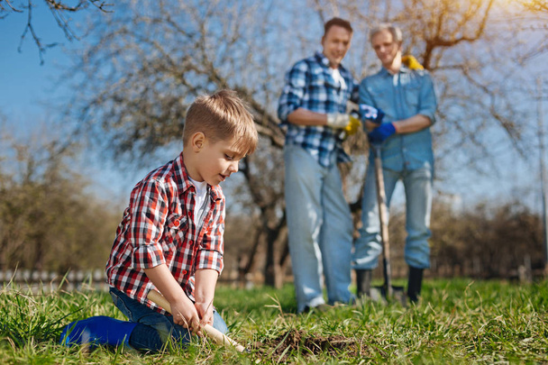 Older generation watching cute child scooping ground - Foto, Imagen