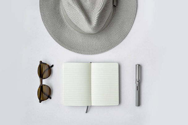 Сонцезахисні окуляри, блокнот, ручка та капелюх на білому тлі
 - Фото, зображення