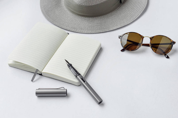 Okulary przeciwsłoneczne, Notatnik, długopis i kapelusz na białym tle - Zdjęcie, obraz