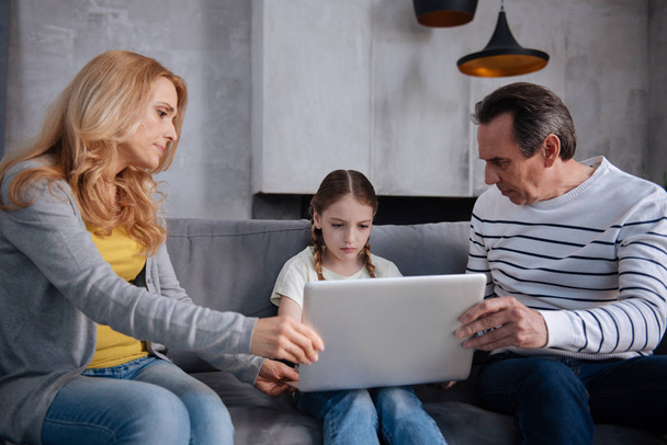 Caring serious parents taking away laptop from kid at home - Foto, Imagen