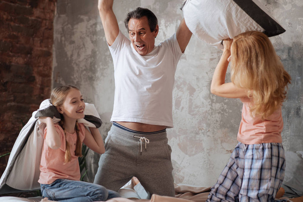 Active famille enchantée profiter de bataille d'oreillers à la maison
 - Photo, image