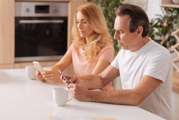 Obsessed mature couple showing addiction to the gadgets at home - Photo, image