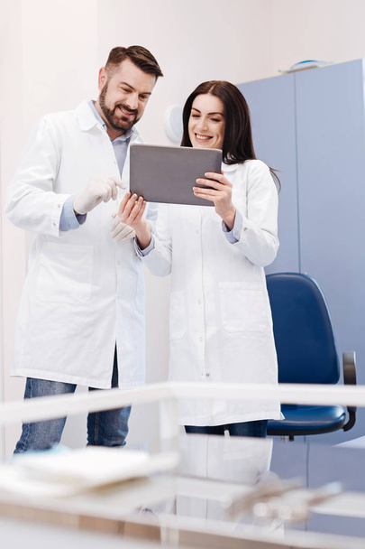 Delighted cheerful doctors looking at the tablet screen - 写真・画像