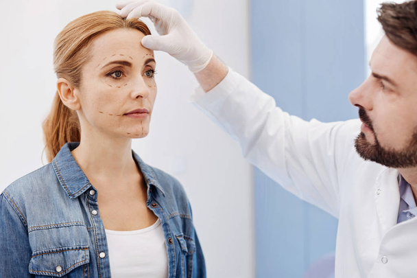 cosmetic surgeon examining his patients face - Fotoğraf, Görsel