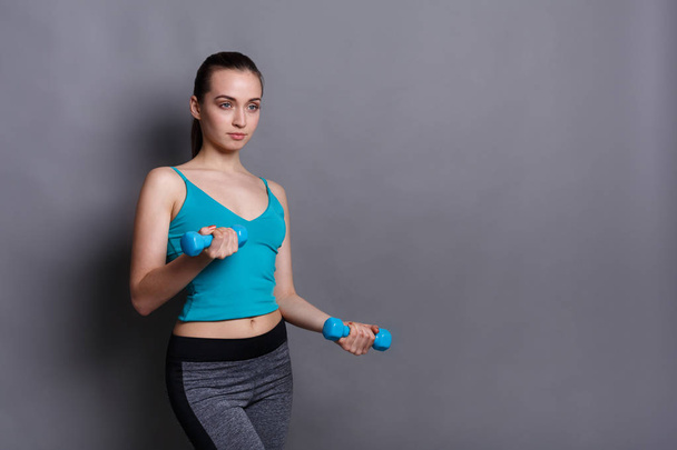 Fitness modèle femme avec haltères en arrière-plan studio
 - Photo, image