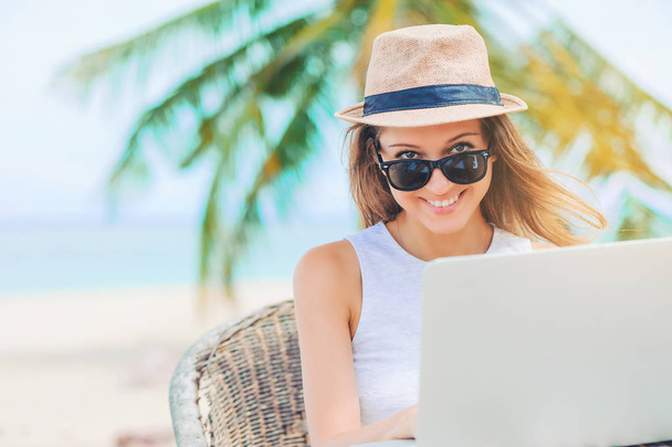 Young woman working in laptop on the beach. Freelance work - Foto, afbeelding
