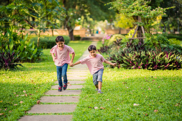 Little sibling asian boy running together in the park with happy together summer time - Foto, Imagen