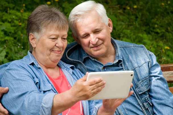 A couple of retired people use a tablet to find information on t - Фото, зображення