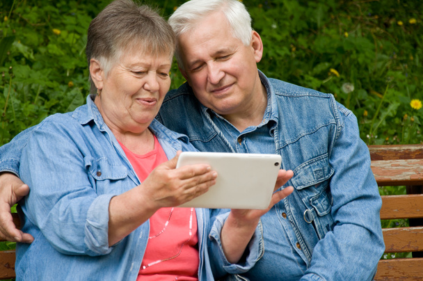 Ένα ζευγάρι από συνταξιούχους Χρησιμοποιήστε ένα δισκίο για να βρείτε πληροφορίες σχετικά με t - Φωτογραφία, εικόνα