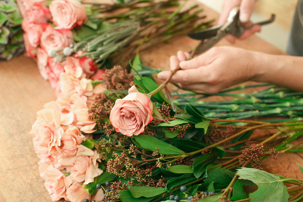 Man assistant in flower shop delivery make rose bouquet closeup - Fotografie, Obrázek